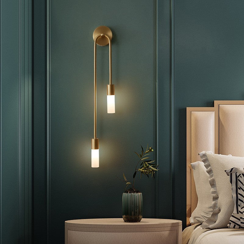 Aplique de pared LED dorado Hilara junto a un cabecero – imagen 3