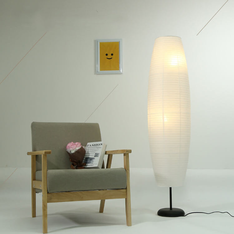 Lámpara de pie de papel estilo farol Velarda – junto a un sillón de madera