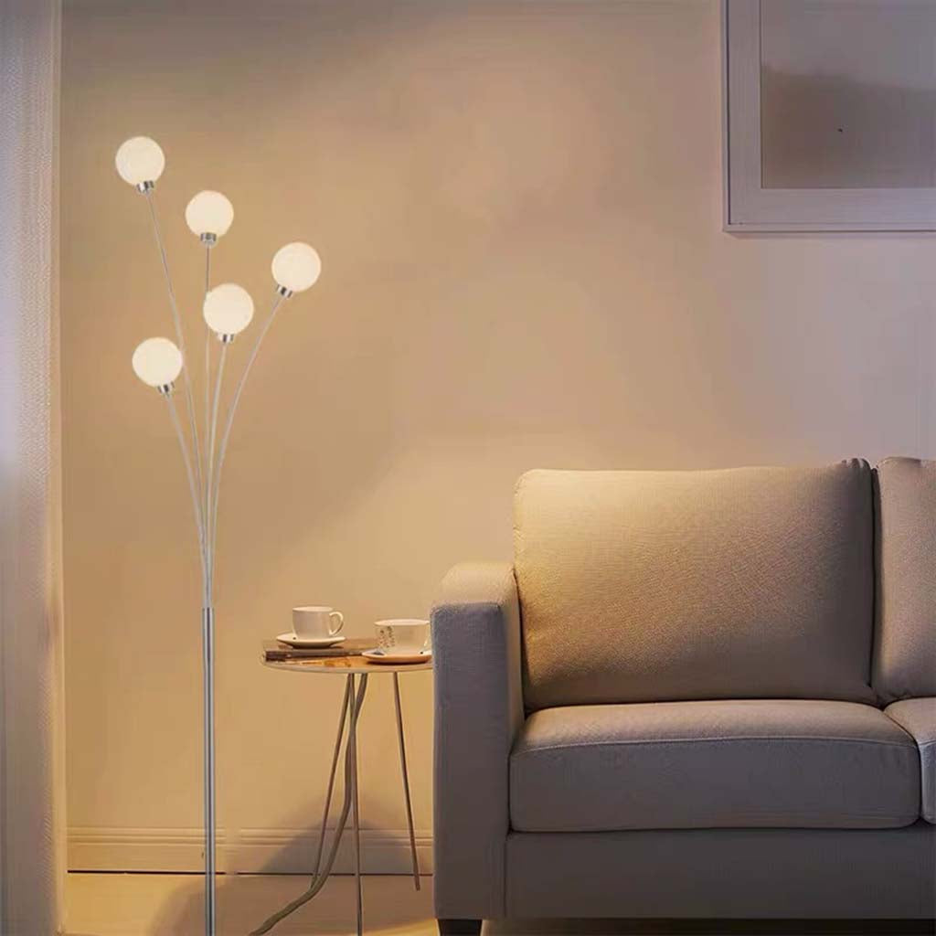 Lámpara de pie con globos de cristal Ramillo – encendida junto a un sofá