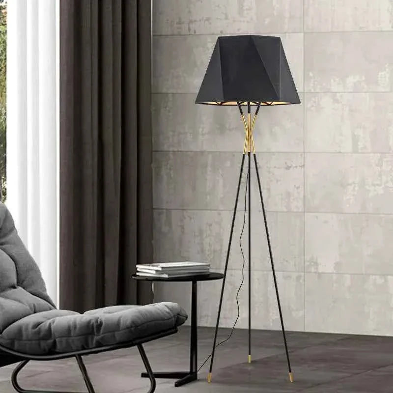 Lámpara de pie trípode Trivena – dorada junto a una chaise longue