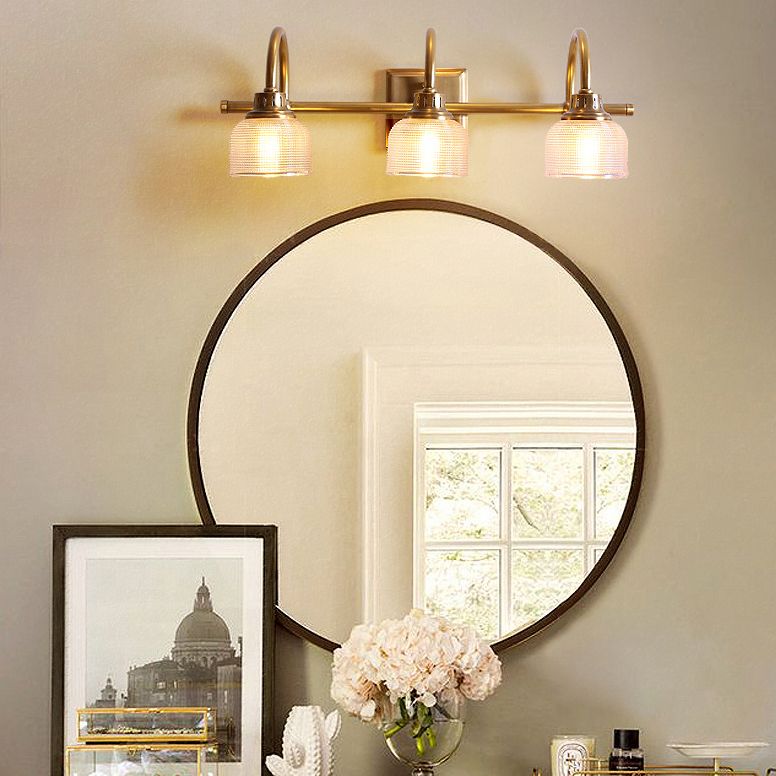 Aplique de pared Yarela con cristal estriado y latón – versión de 3 luces sobre un espejo redondo