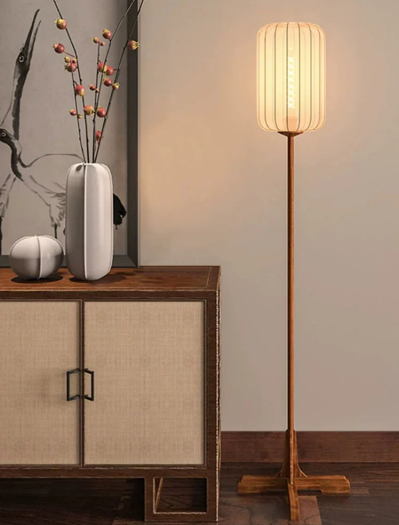 Lámpara de pie farol de tela Tolena – encendida junto a un aparador de ratán