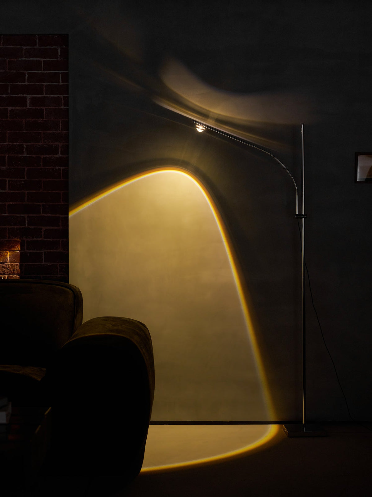 Lámpara de pie LED arqueada Vareta – proyectando un arco de luz en un rincón oscuro