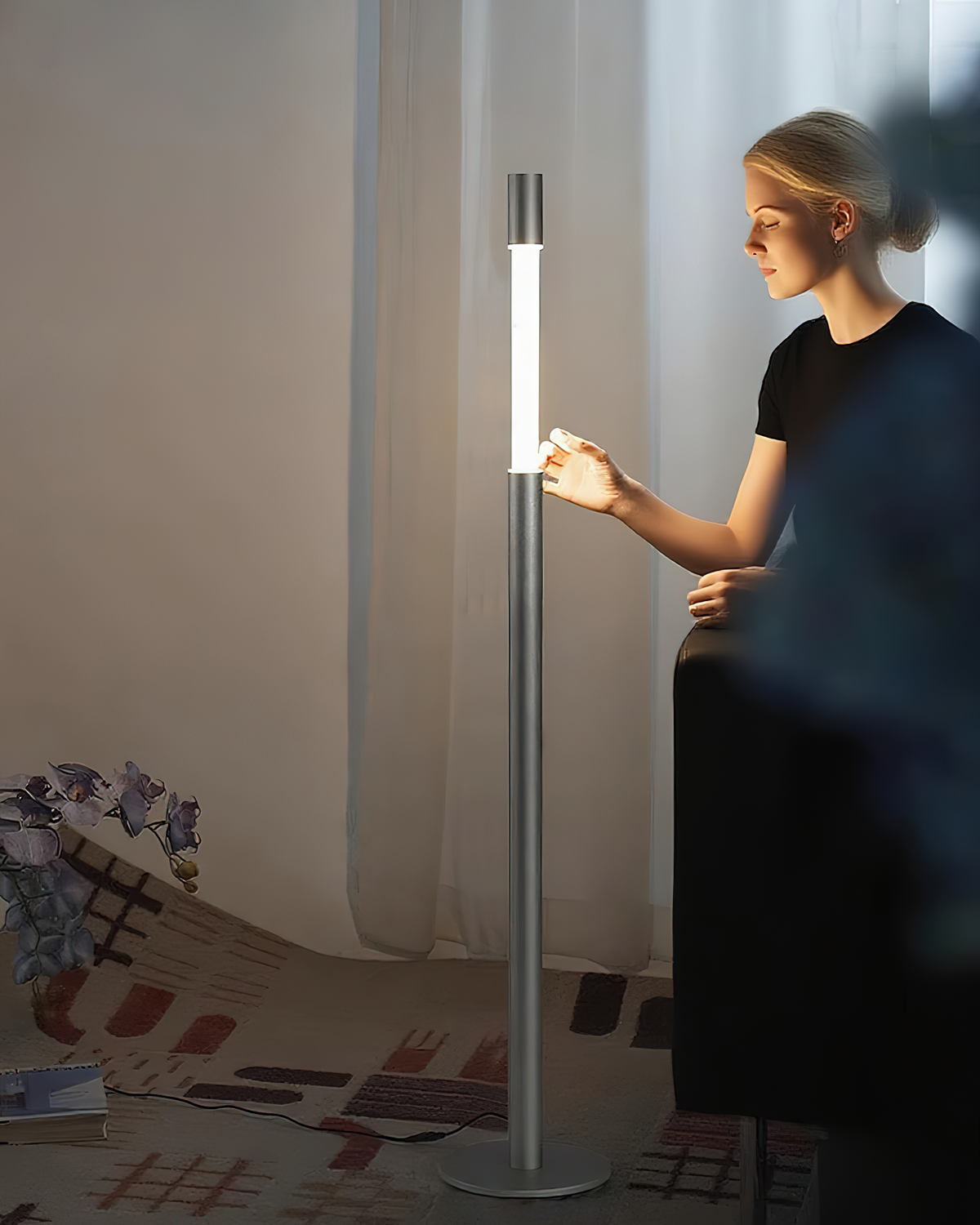 Lámpara de pie LED columna Tizona – plateada junto a un sofá