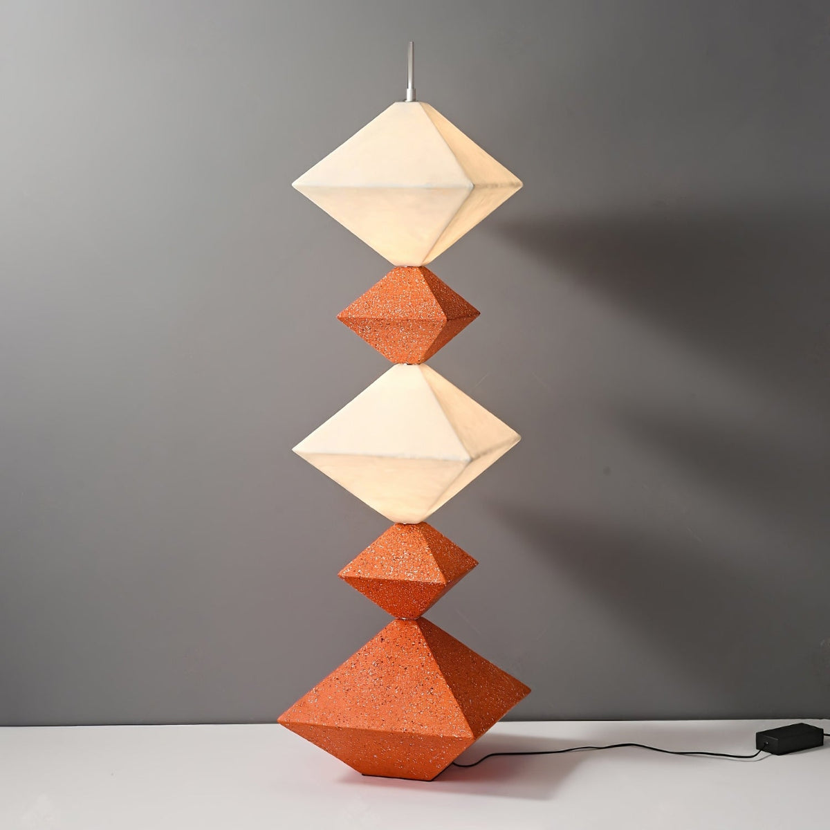 Lámpara de pie LED con rombos apilados Peluma – en naranja y blanco sobre fondo gris