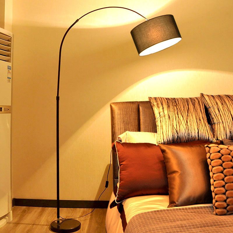 Lámpara de pie de arco Tendela – en negro junto a un sofá