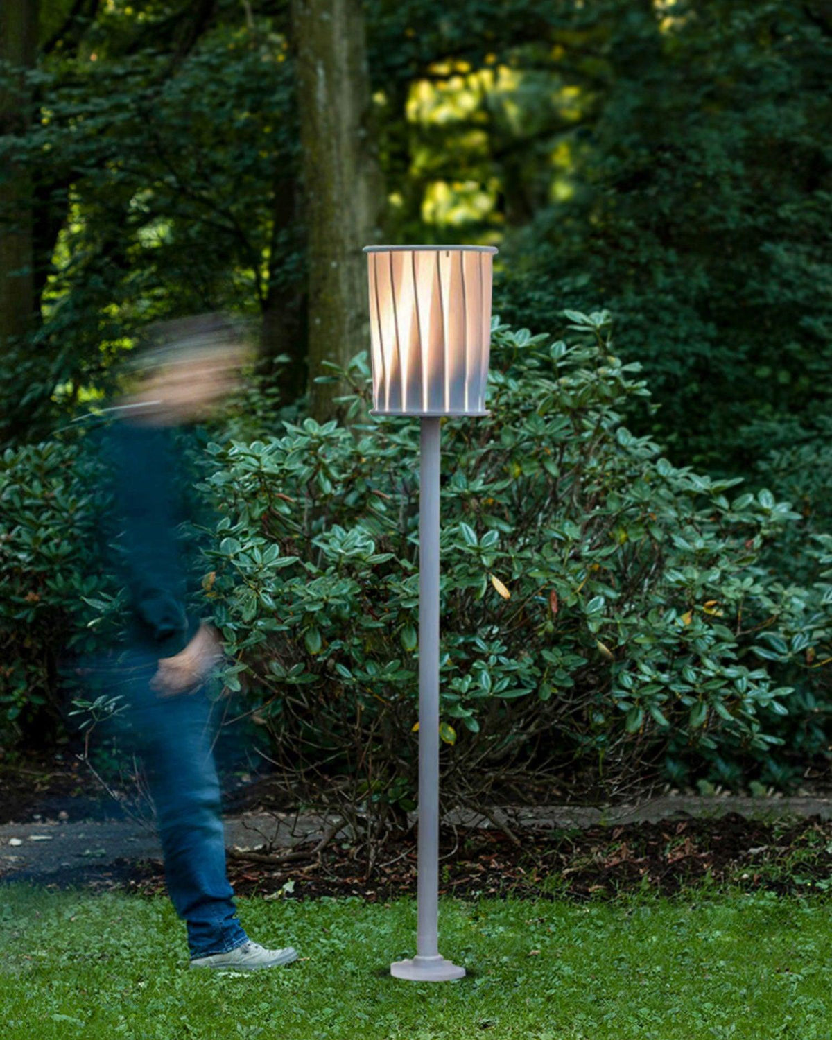 Lámpara de pie exterior Ortiva – en un jardín frondoso