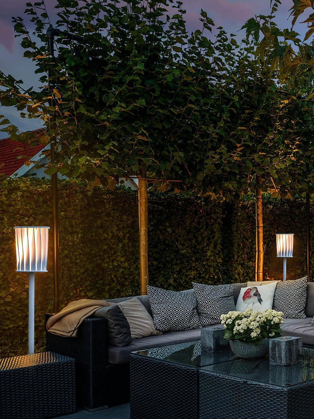 Lámpara de pie exterior Ortiva – junto a un sofá de jardín