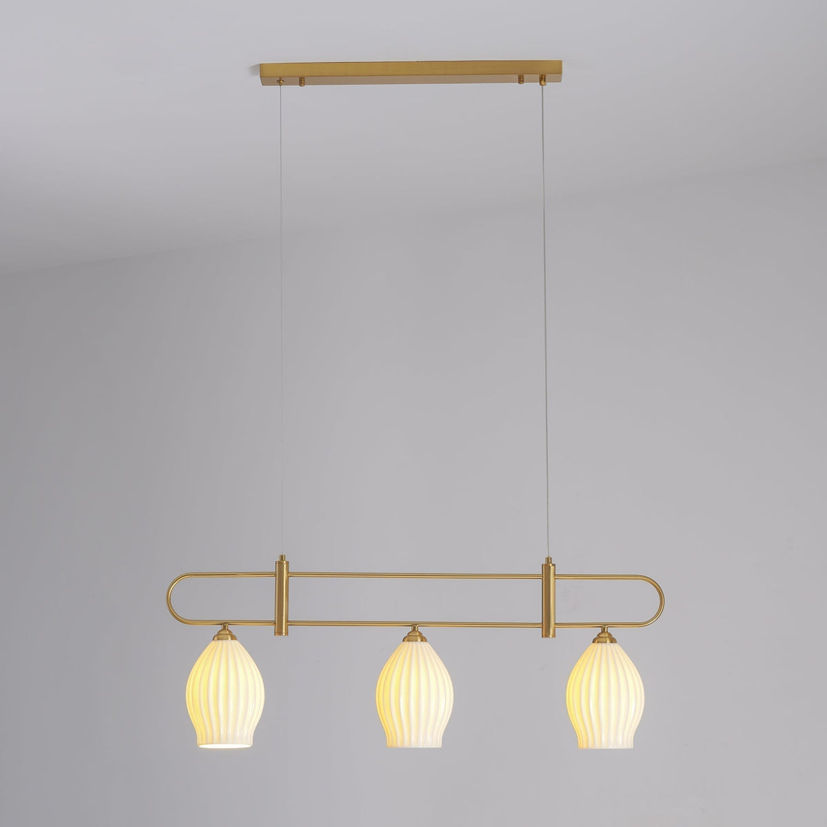 Lámpara colgante lineal de cerámica Gajela – cobre de tres luces encendida