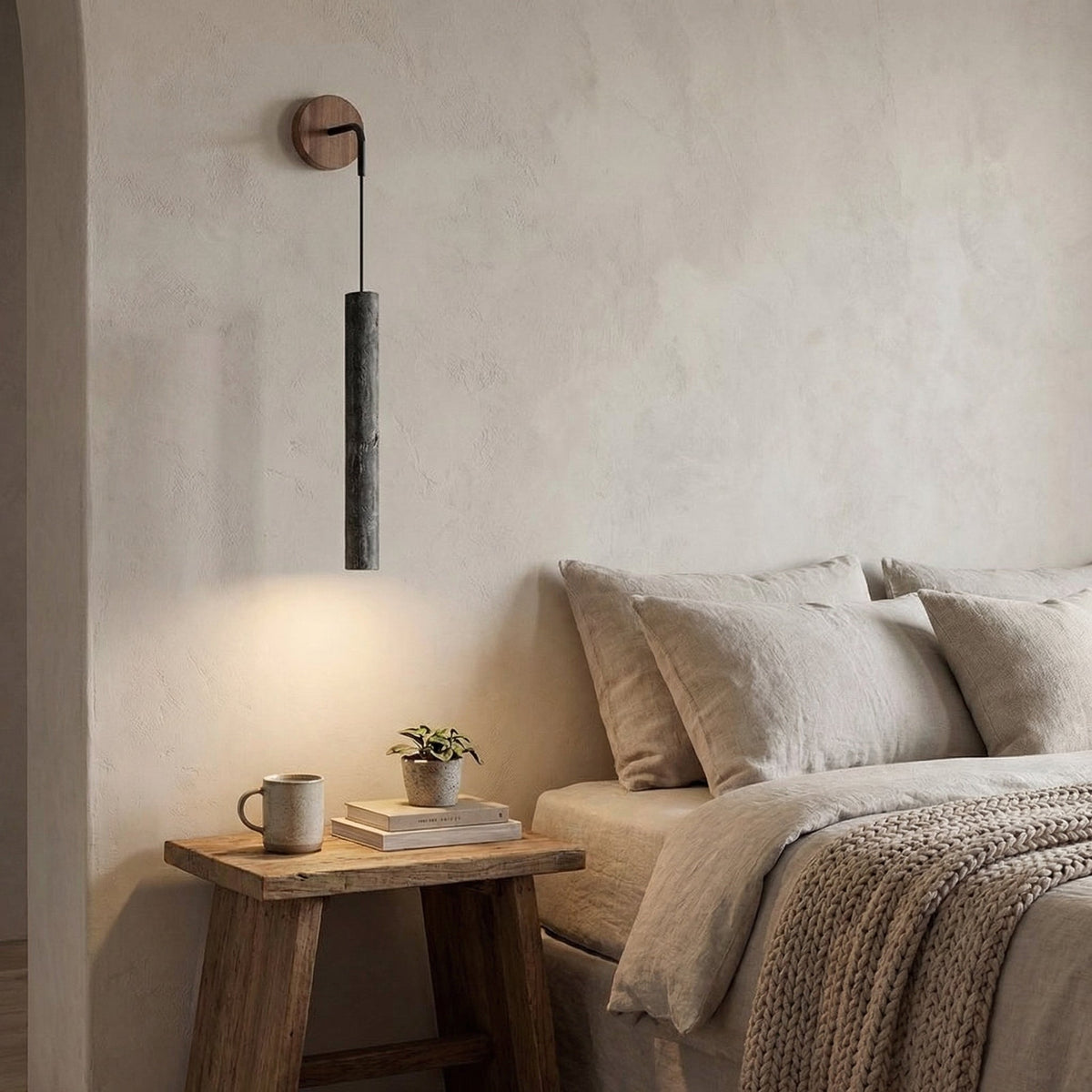 Aplique de pared con tubo de travertino Velcana – travertino negro sobre una mesilla de noche