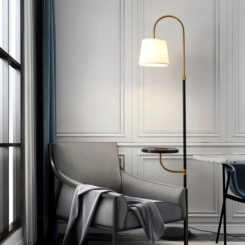 Lámpara de pie de arco con mesita Ulmena – con pantalla de tela junto a un sillón