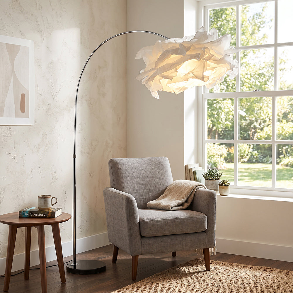 Lámpara de pie de arco con pantalla de papel Rizolva – junto a un sillón en un salón