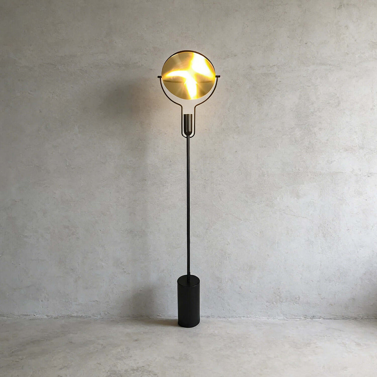 Lámpara de pie Rotisca – encendida junto a una pared de hormigón