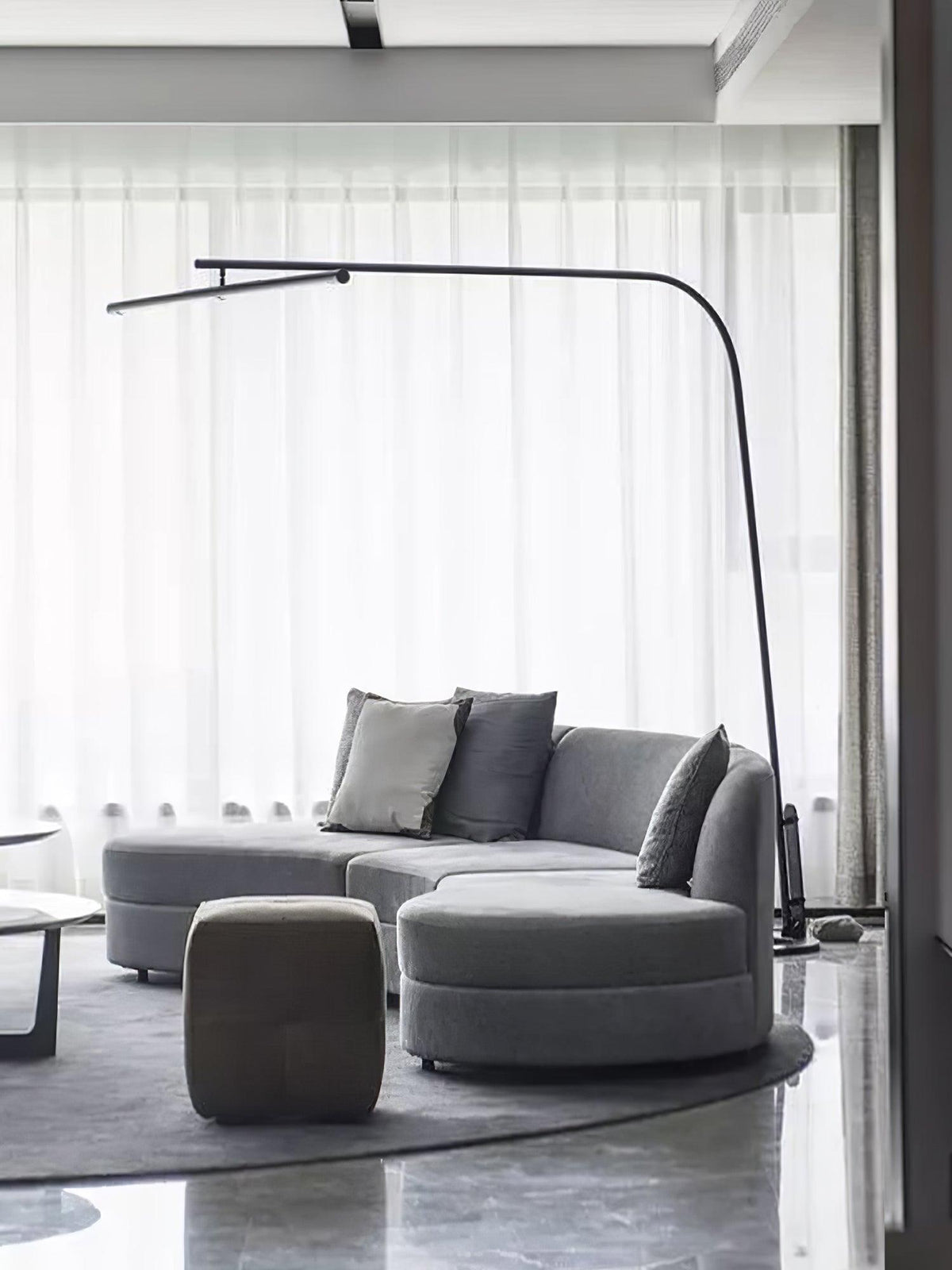Lámpara de pie de arco LED Sigela – sobre un sofá curvo gris