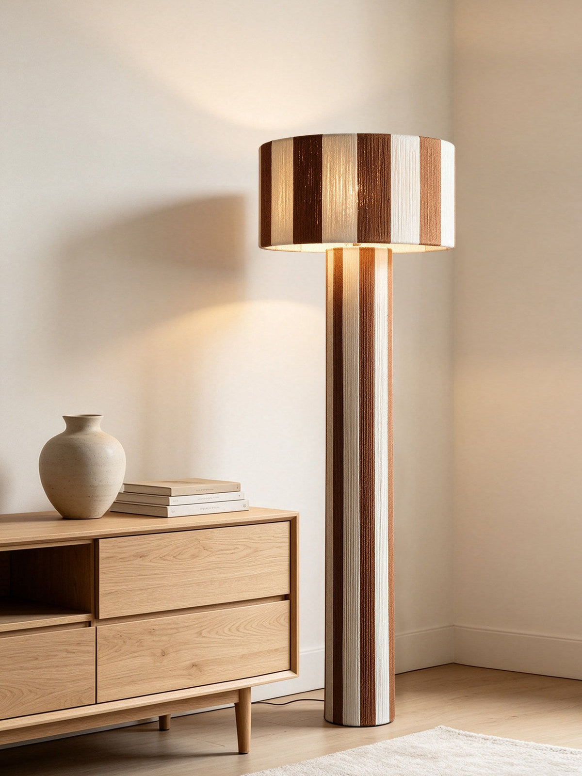 Lámpara de pie columna de hilo a rayas Sombrilda – junto a un mueble de madera