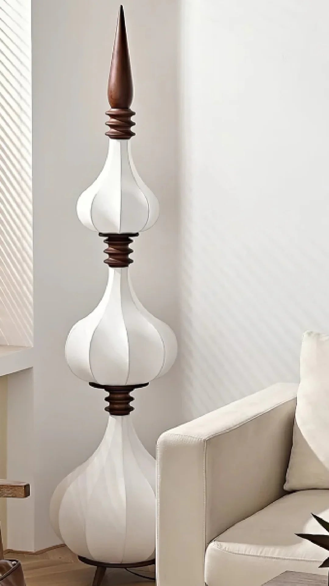 Lámpara de pie de tela y madera Torrina – apagada de tres globos junto a un sillón