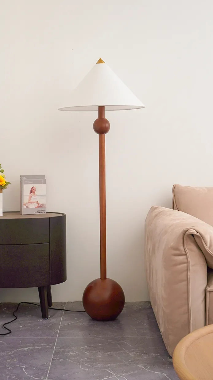 Lámpara de pie de madera Velbora – junto a un sofá rosa