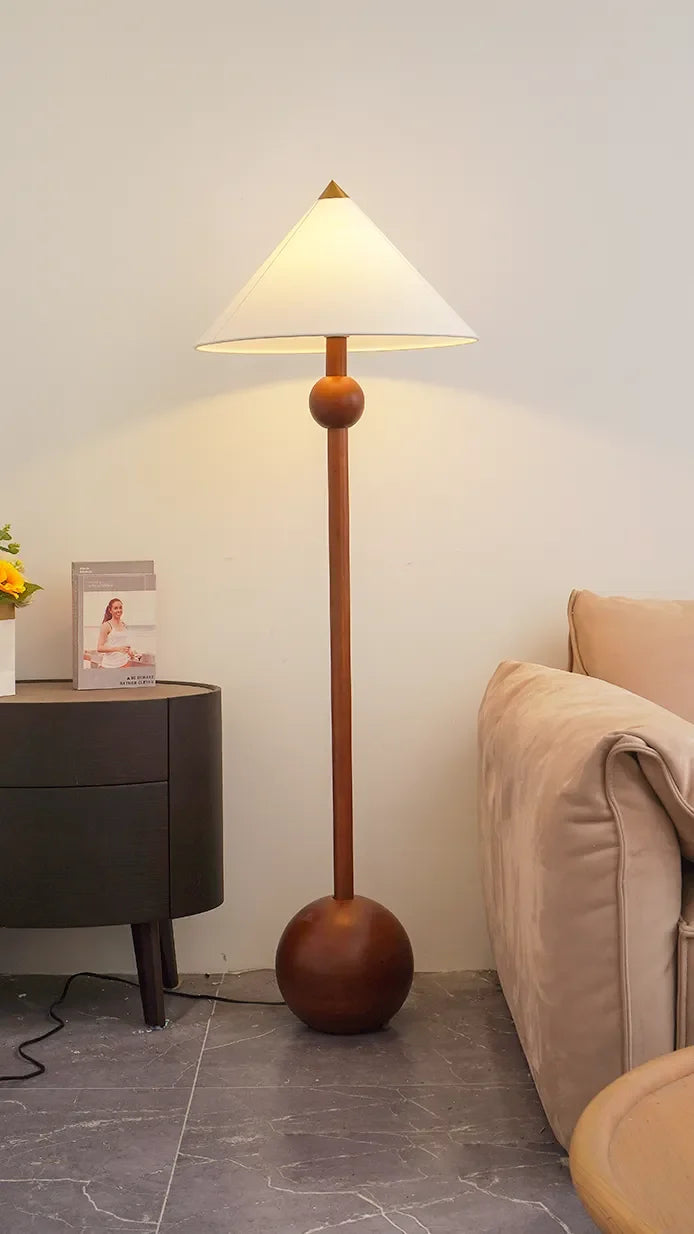 Lámpara de pie de madera Velbora – encendida junto al sofá