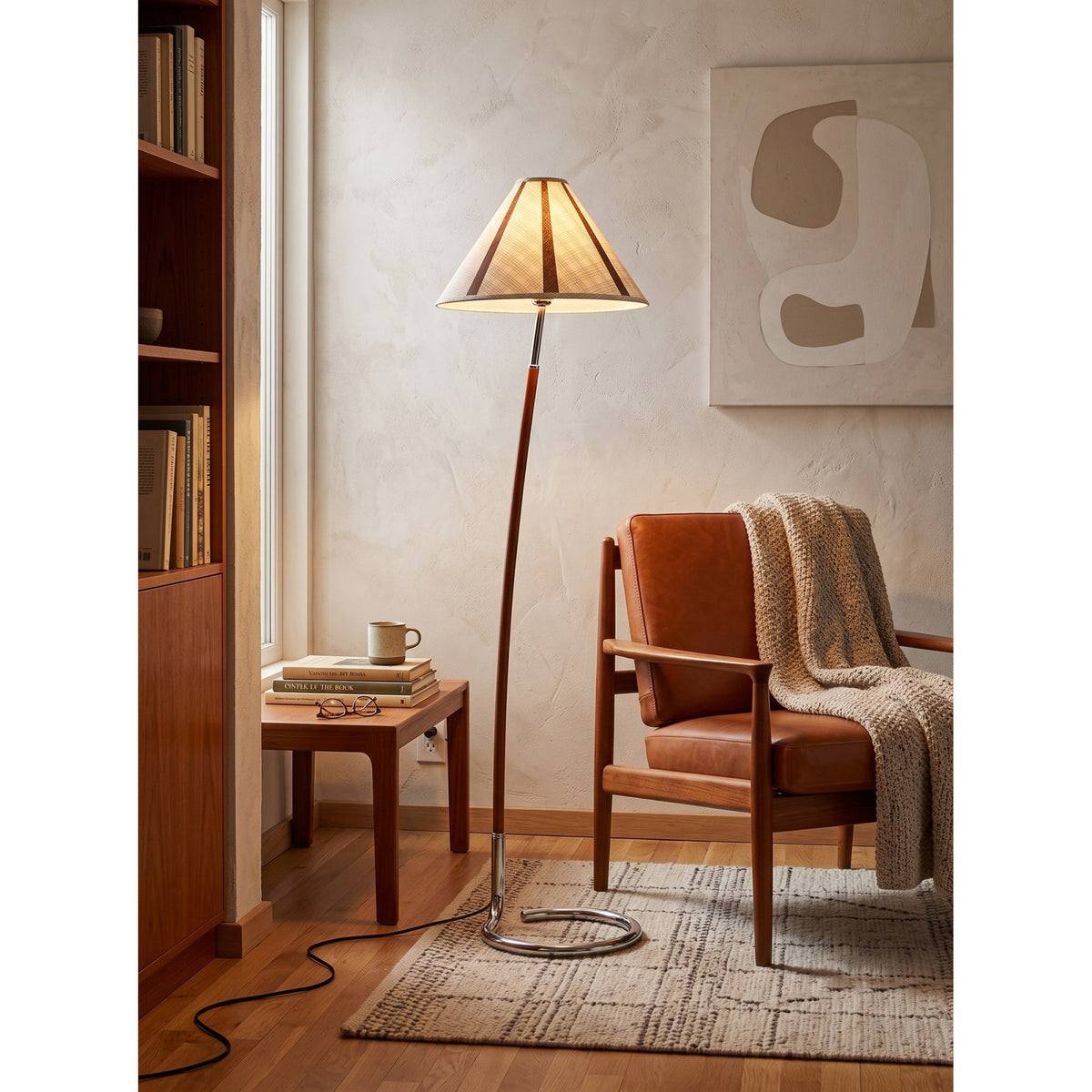 Lámpara de pie de lectura Volutina – junto a un sillón de piel y una manta