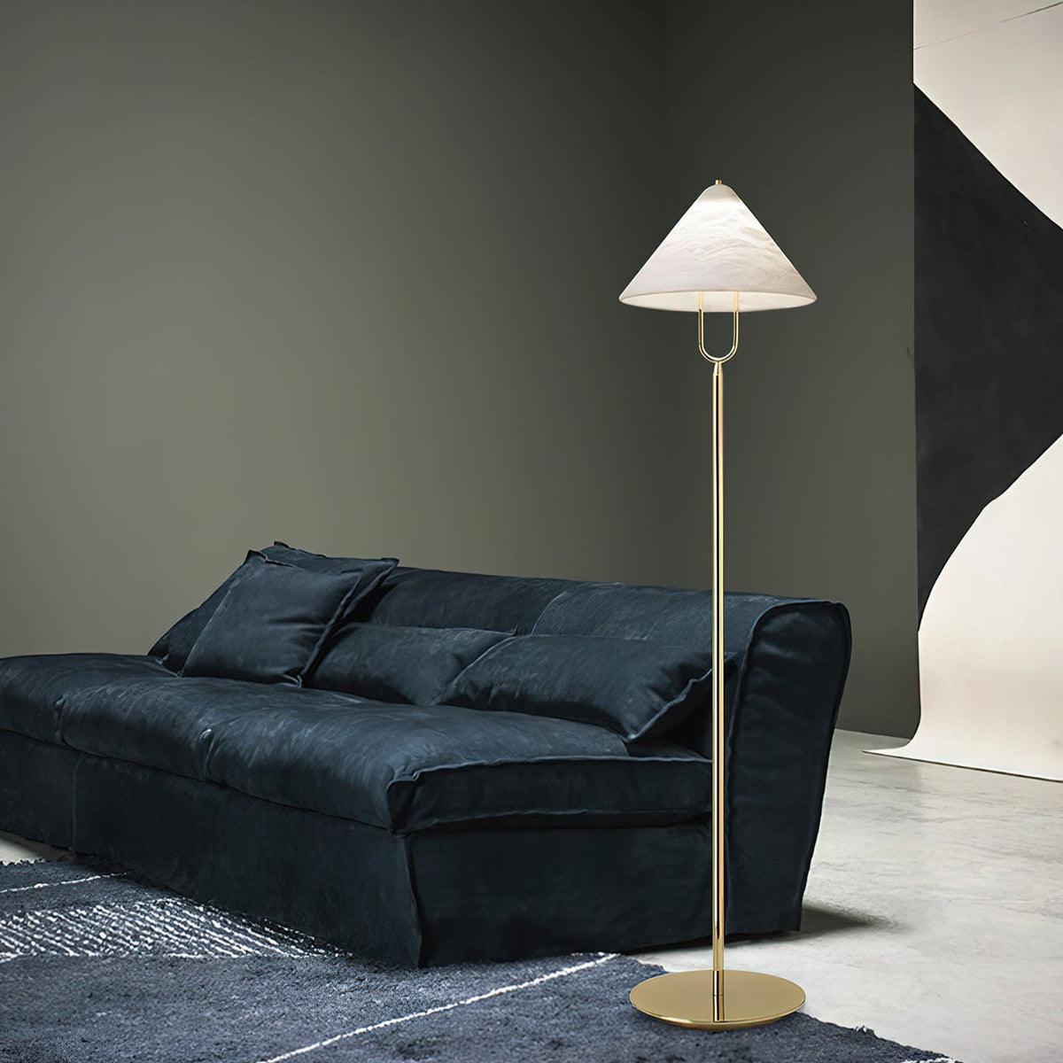 Lámpara de pie Yamira – junto a un sofá azul oscuro