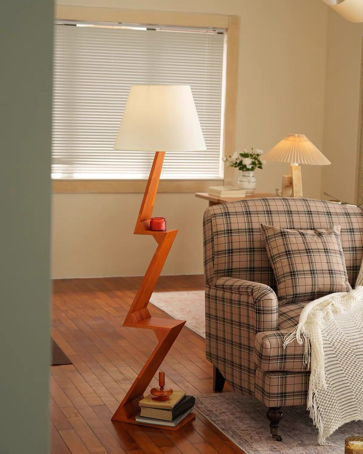 Lámpara de pie de madera en zigzag Zagora – junto a un sillón de cuadros