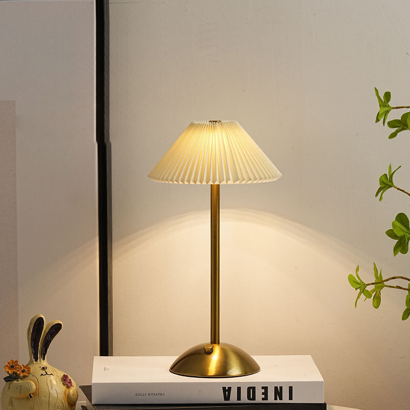 Lámpara de mesa recargable Delisa con pantalla plisada sobre una mesita – imagen 10