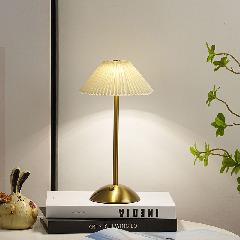 Lámpara de mesa recargable Delisa con pantalla plisada sobre una mesita – imagen 12
