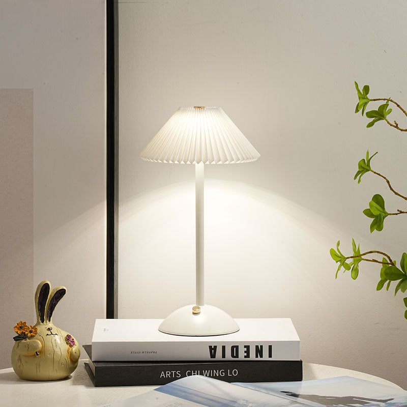 Lámpara de mesa recargable Delisa con pantalla plisada sobre una mesita – imagen 23