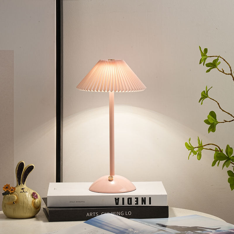 Lámpara de mesa recargable Delisa con pantalla plisada sobre una mesita – imagen 11