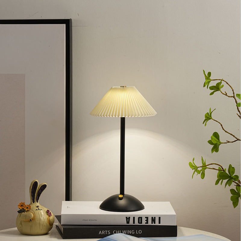 Lámpara de mesa recargable Delisa con pantalla plisada sobre una mesita – imagen 14