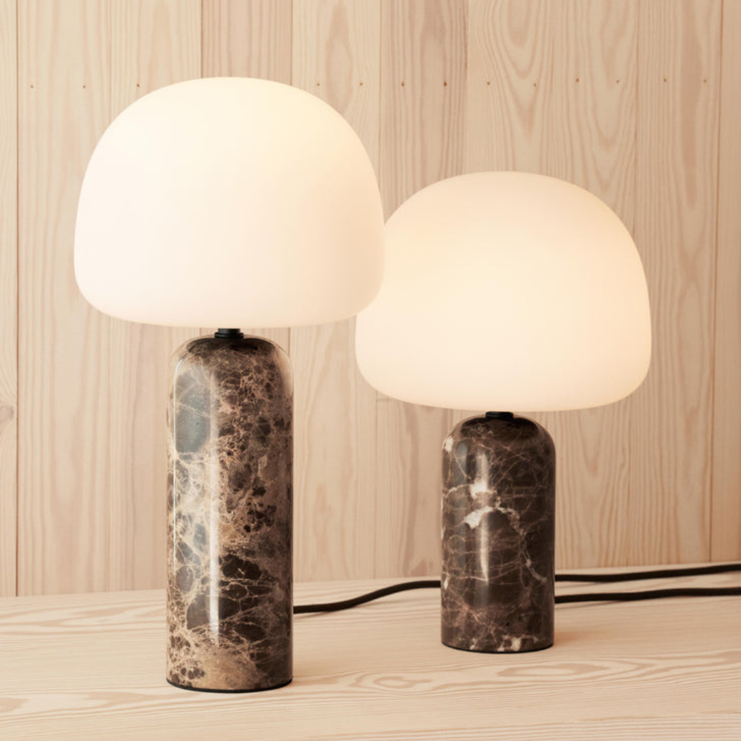Lámpara de mesa de mármol Velmara – dos lámparas encendidas sobre una cómoda