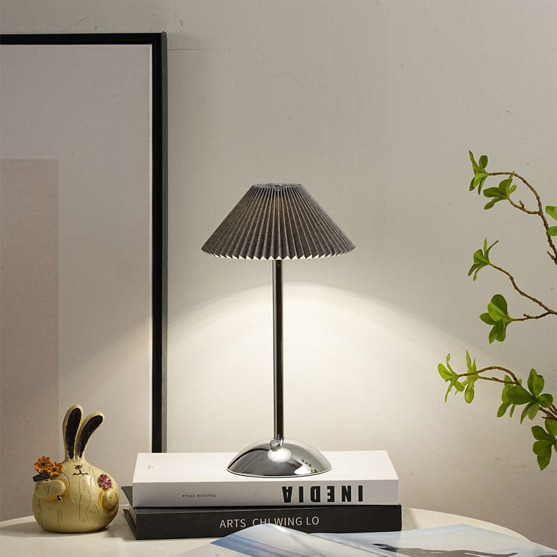 Lámpara de mesa recargable Delisa con pantalla plisada sobre una mesita – imagen 13