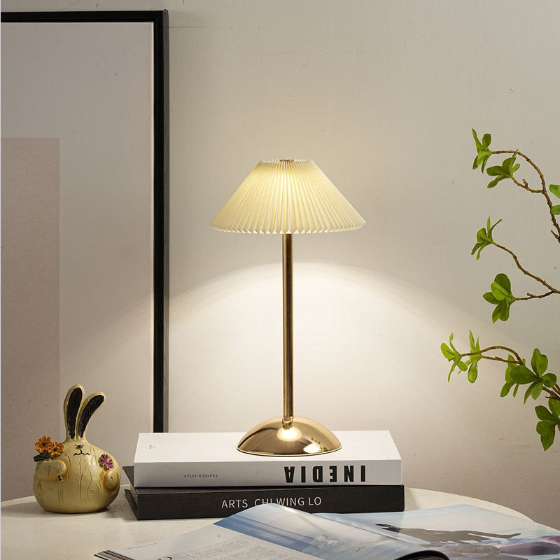 Lámpara de mesa recargable Delisa con pantalla plisada sobre una mesita – imagen 21