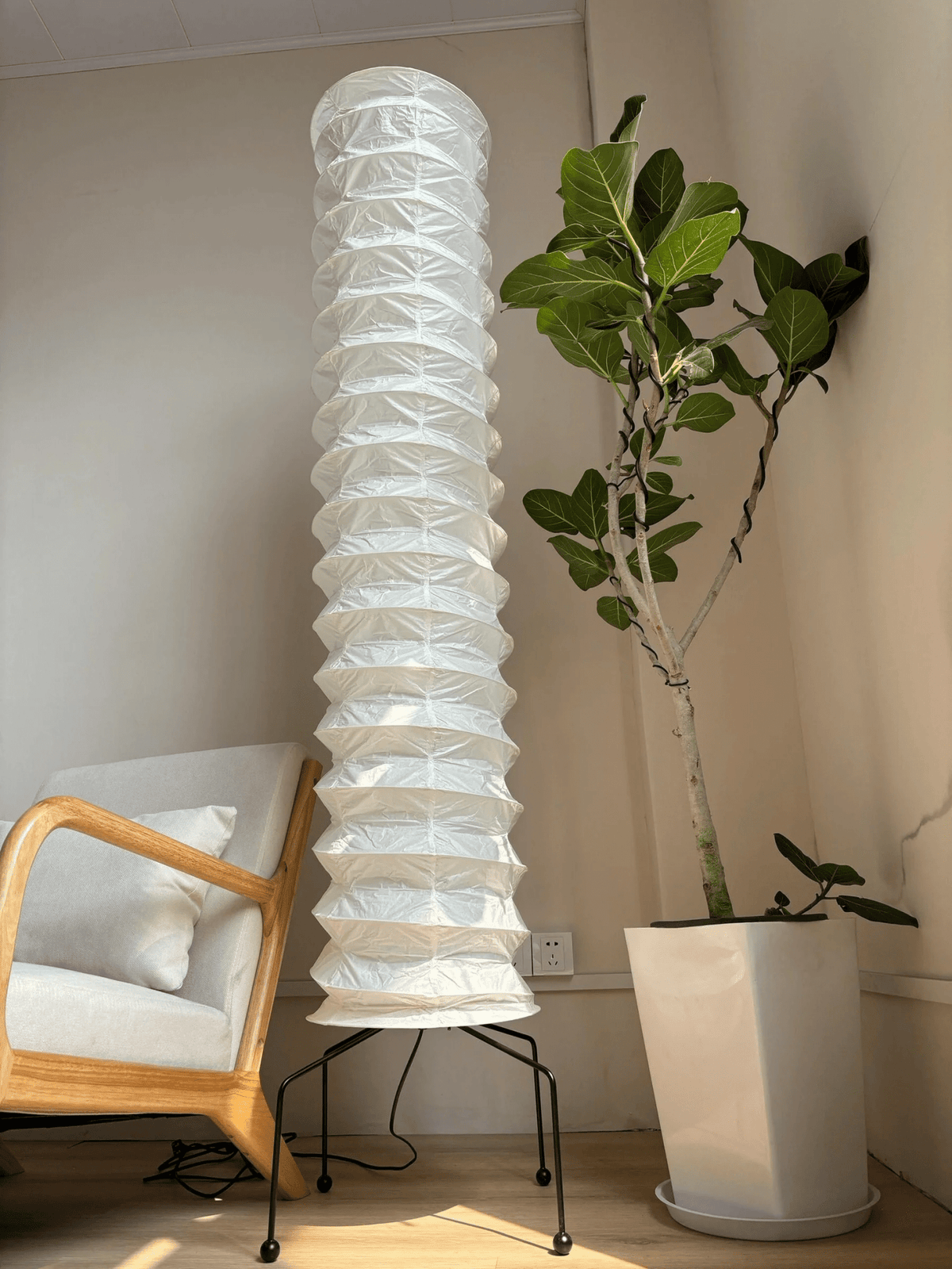 Lámpara de pie columna de papel de arroz Kiluma – junto a una planta y un sillón