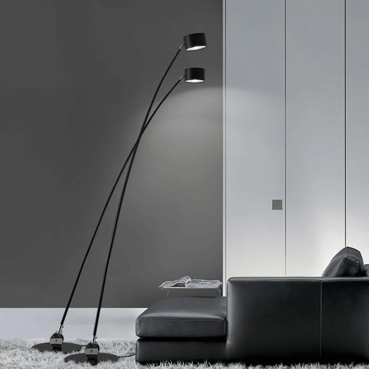 Lámpara de pie LED de brazo curvado Tallira – dos lámparas sobre un sofá negro