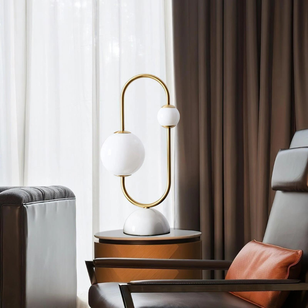 Lámpara de mesa Jeluna con aro dorado y globos de vidrio – junto a un sillón en el salón