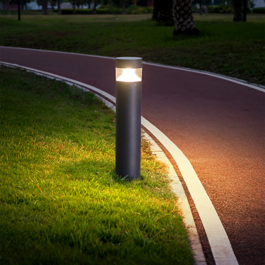 Baliza de jardín LED Olbera – remate plano encendido junto a un camino