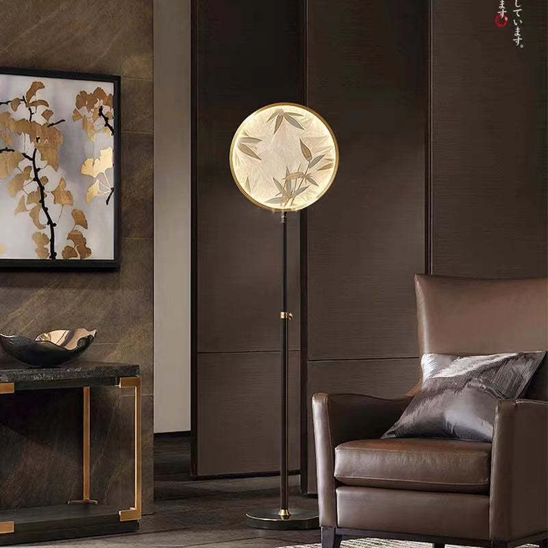 Lámpara de pie con disco de vidrio Zenavi – junto a un sillón de piel