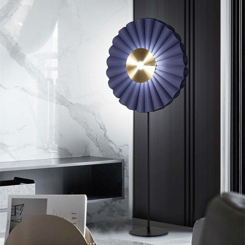 Lámpara de pie LED con disco plisado Zirena – azul junto a una pared de mármol