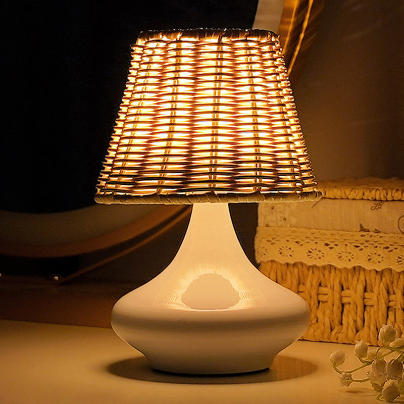 Lámpara de mesa de ratán Tejina – base blanca encendida en el dormitorio