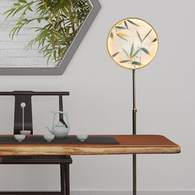 Lámpara de pie con disco de vidrio Zenavi – junto a una mesa de té