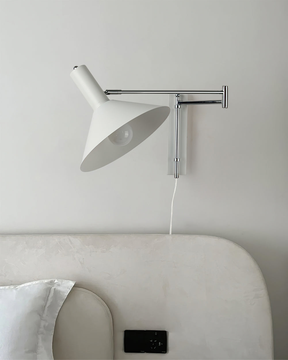 Aplique de pared articulado Brazola junto a un sillón de lectura – imagen 12