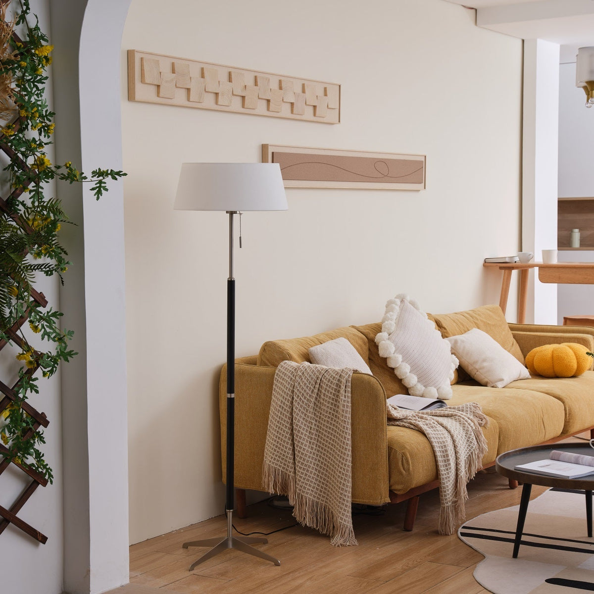 Lámpara de pie con base trípode y pantalla de tela blanca Iluma – apagada en un salón con arco