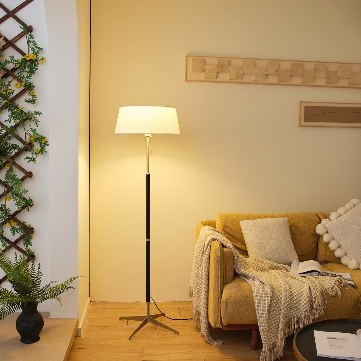Lámpara de pie con base trípode y pantalla de tela blanca Iluma – encendida en un salón cálido