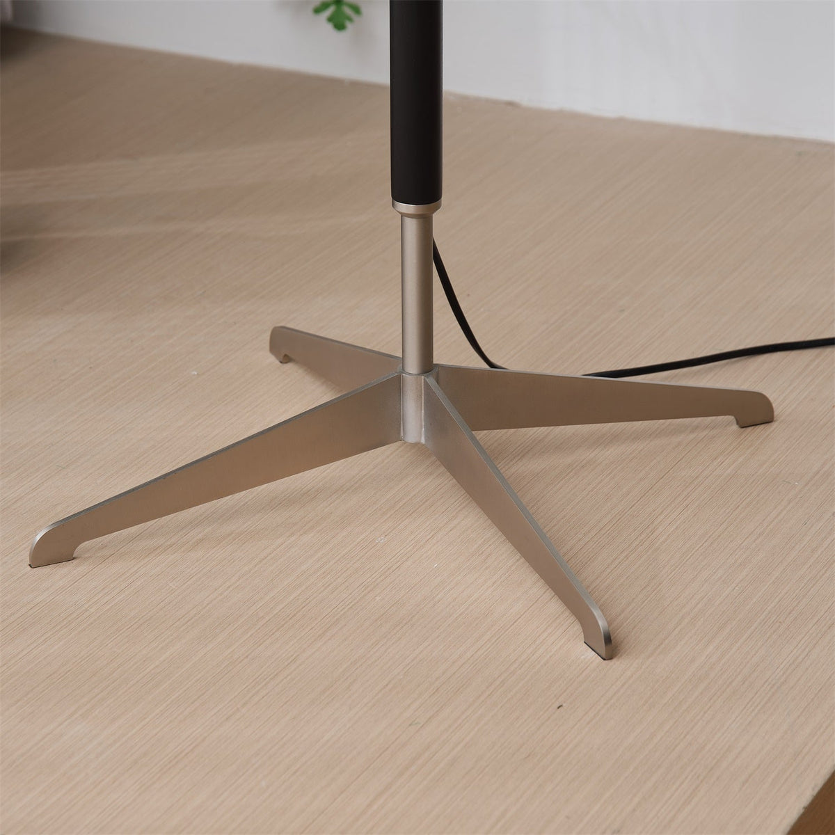 Lámpara de pie con base trípode y pantalla de tela blanca Iluma – detalle de la base de tres patas sobre madera