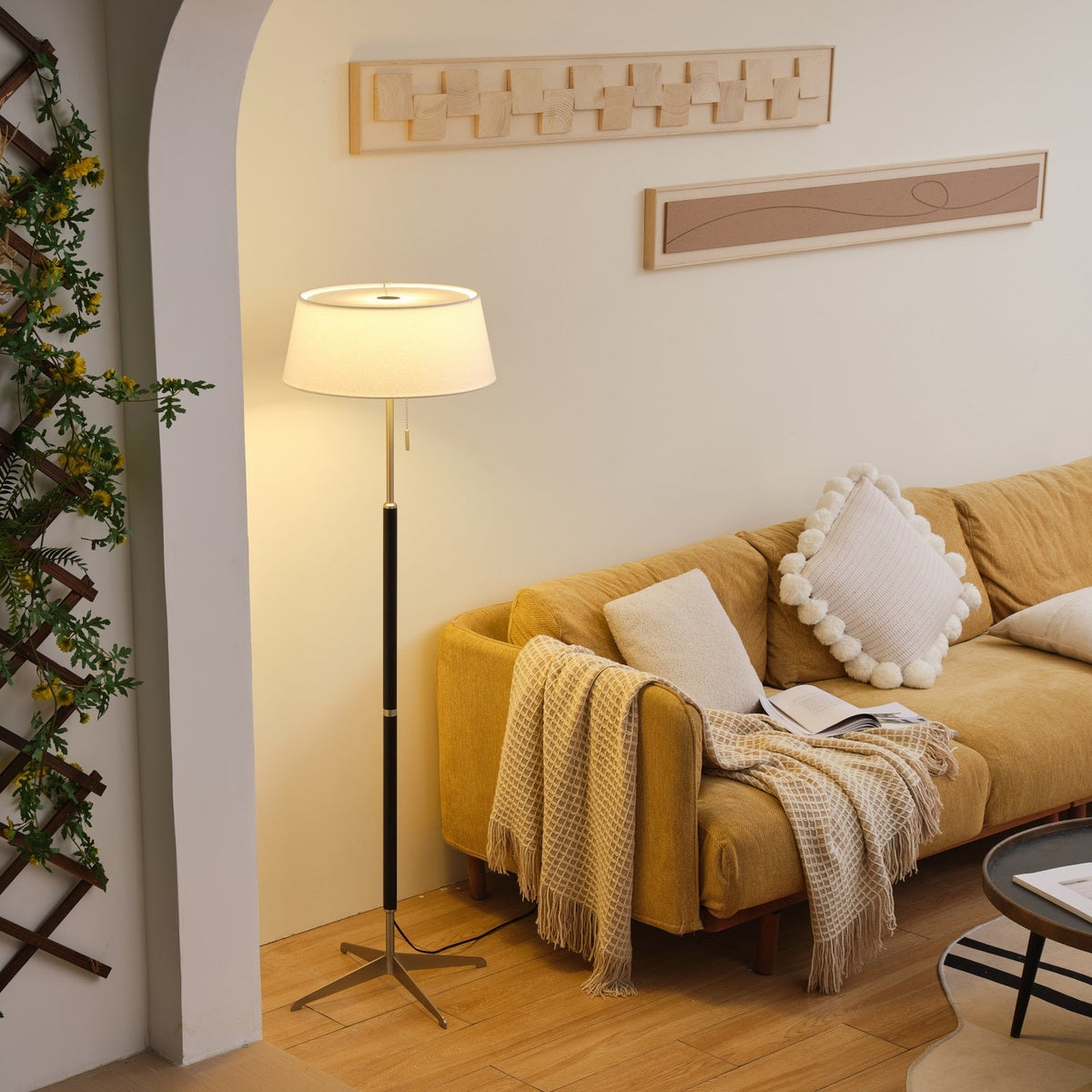 Lámpara de pie con base trípode y pantalla de tela blanca Iluma – encendida en un salón luminoso