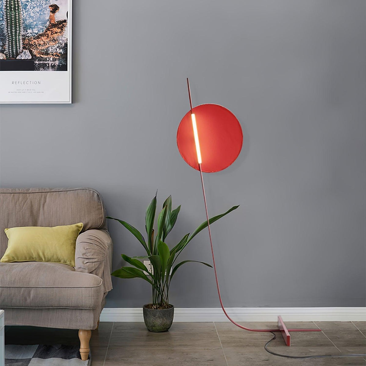 Lámpara de pie LED roja con disco de luz y varilla curva Oriola – junto a un sillón y una planta