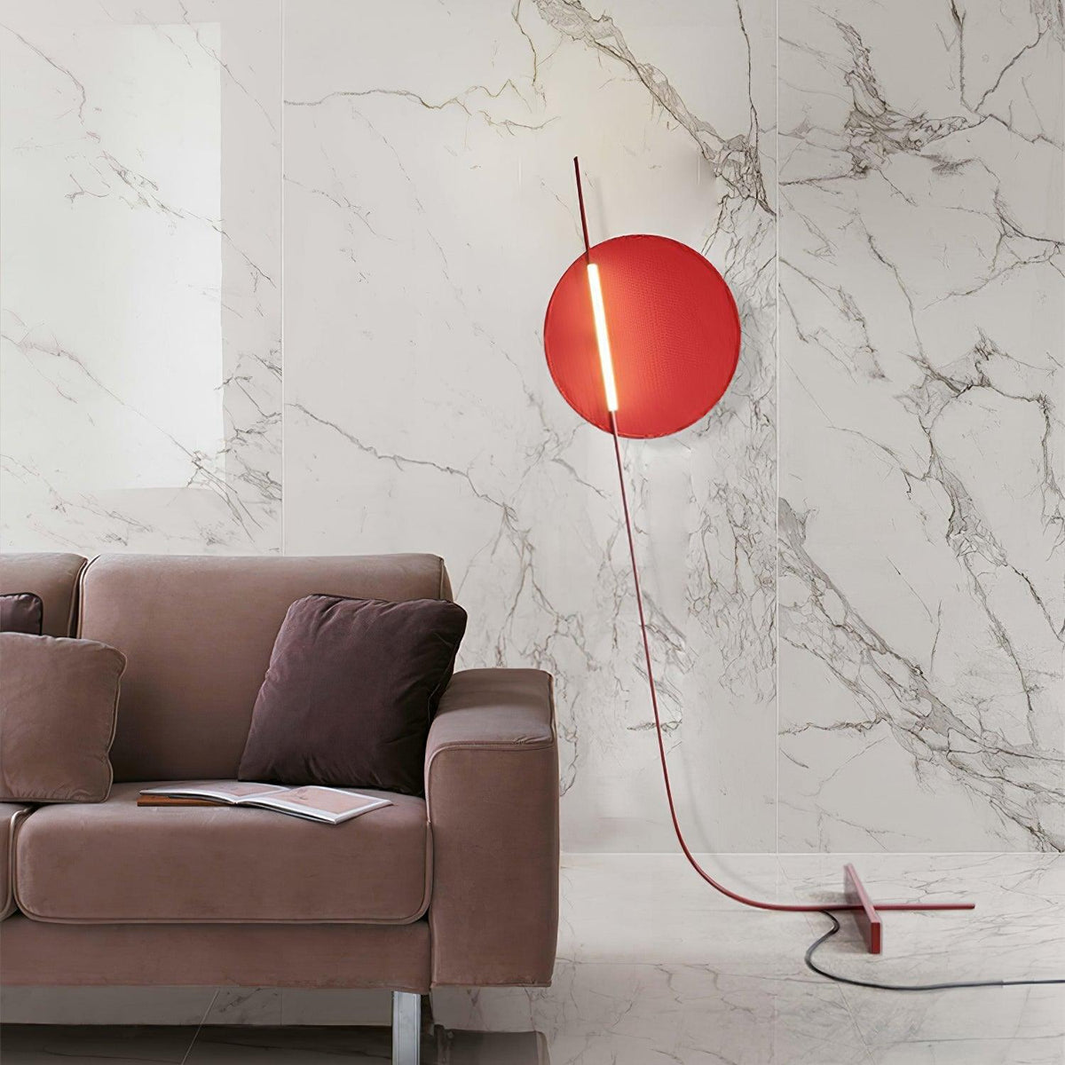 Lámpara de pie LED roja con disco de luz y varilla curva Oriola – junto a un sofá de mármol