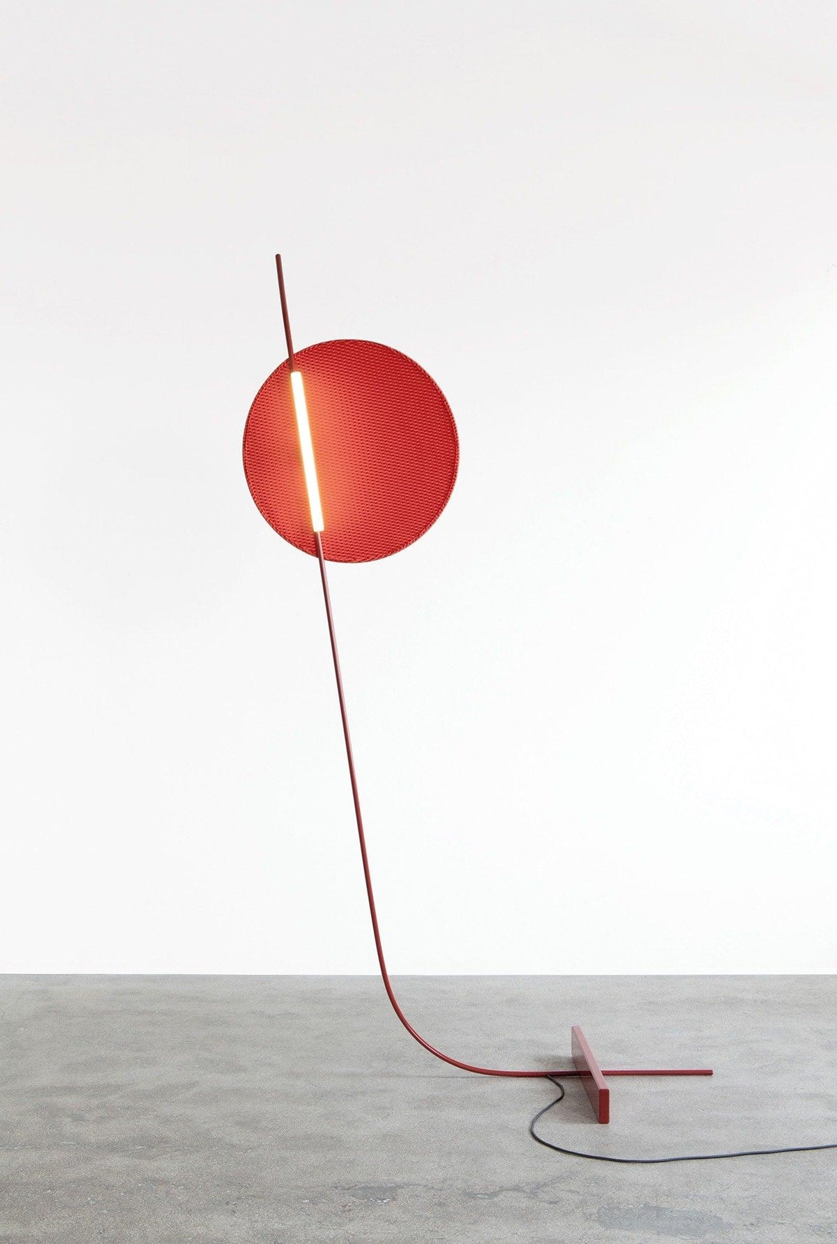 Lámpara de pie LED roja con disco de luz y varilla curva Oriola – sobre suelo de cemento