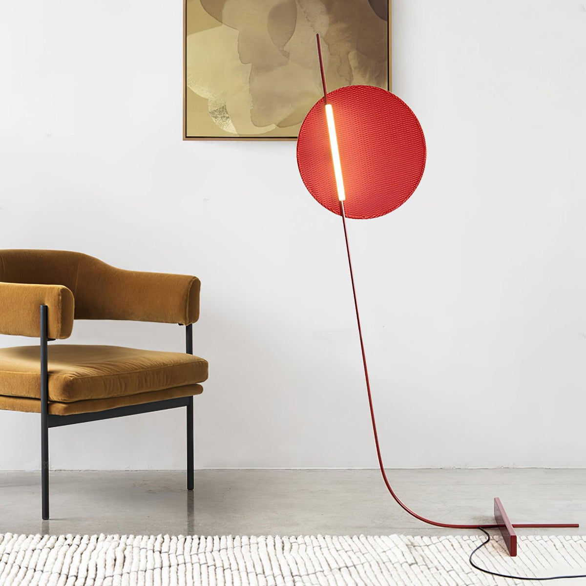 Lámpara de pie LED roja con disco de luz y varilla curva Oriola – en un rincón junto a una butaca ocre